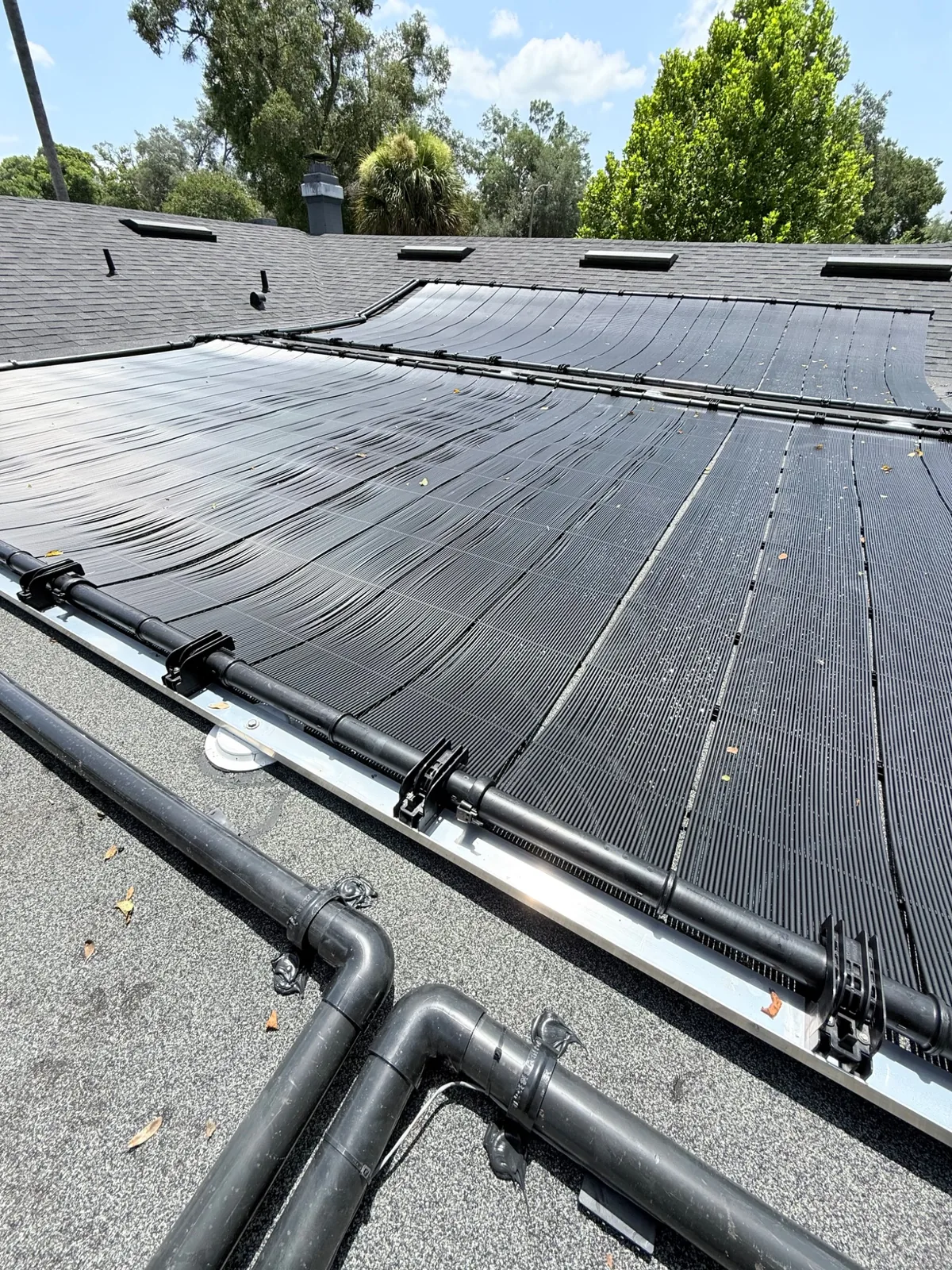 Close-up of installed solar pool heating collectors and roof plumbing.